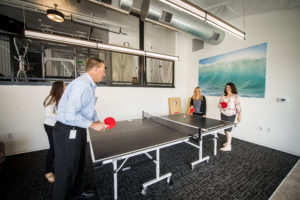 remarkable health employees playing ping pong during break